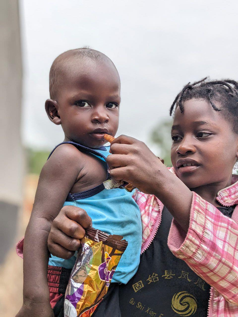A child shares food with a younger sibling